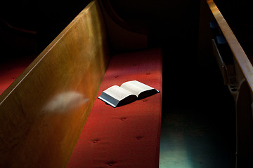 Image showing Open Bible Lying on Church Pew in Narrow Sunlight Band