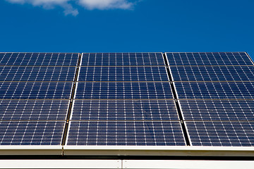 Image showing Row of Photovoltaic Solar Panels on Roof Against Blue Sky      