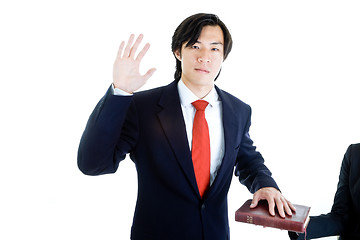 Image showing Asian Man Raised Hand Swearing on Bible Isolated White Backgroun