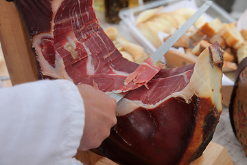 Image showing A hand cutting prosciutto