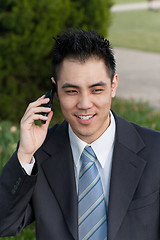 Image showing Asian Businessman Holding Cell Phone Outside Park