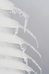 Image showing Row of Icicles Hanging off a Roof Gray Sky Background