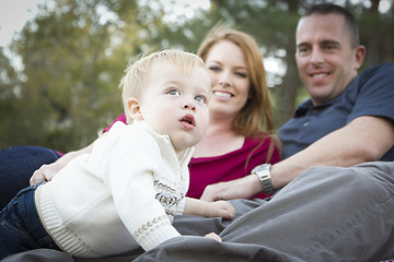 Image showing Cute Child Looks Up to Sky as Young Parents Smile