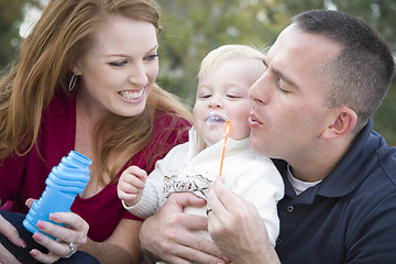 Image showing Young Parents Blowing Bubbles with their Child Boy in Park