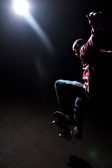 Image showing Skateboarder Jumping Under Dramatic Lighting