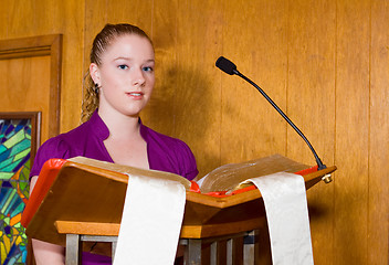 Image showing Young Caucasian Woman Reading from Bible at Church Lectern 