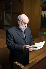 Image showing Standing Senior Caucasian Man Reading Hymnal In Church Pew