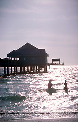 Image showing People wading in the water near pier