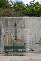 Image showing Green bench set against a tall concrete wall