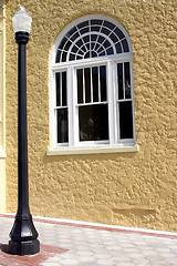 Image showing A black lamppost and window against yellow stucco wall