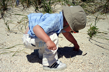 Image showing Boy on beach picking up pebbles