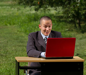 Image showing man with red laptop working outdoors