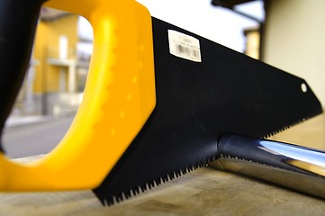 Image showing Wooden saw used for cutting a metal pipe