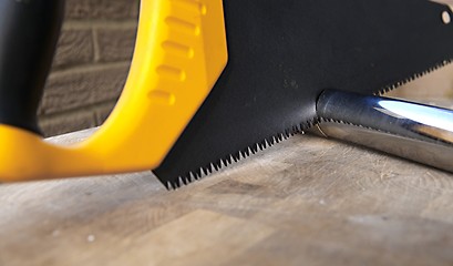 Image showing Wooden saw used for cutting a metal pipe