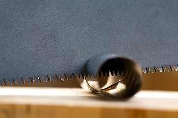 Image showing Wooden saw used for cutting a metal pipe