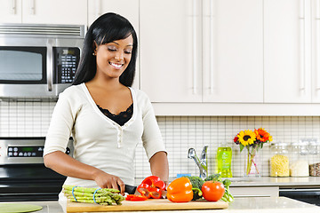 Image showing Young woman cutting vegetables in kitchen