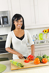 Image showing Young woman cutting vegetables in kitchen