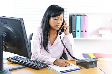 Image showing Serious black businesswoman on phone at desk