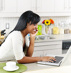 Image showing Woman using computer in kitchen