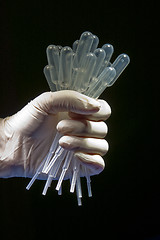 Image showing Hand in white gloves holding many pipettes