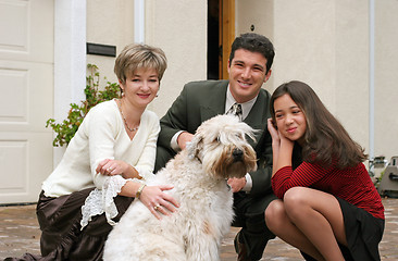 Image showing Happy family with a dog in front of the home