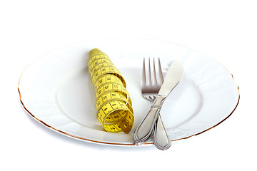 Image showing Diet concept. Knife, fork and measuring tape on a plate.