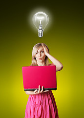 Image showing blonde in pink dress with laptop and bulb