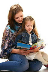 Image showing Young woman reads a book a little girl.