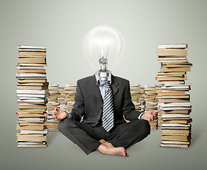 Image showing businessman in lotus pose and lamp-head with many books near