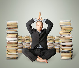 Image showing businessman in lotus pose with many books near