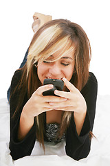 Image showing Teenage girl chatting with cell phone lying down  - isolate 