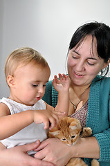 Image showing mother and daughter playing with a cat