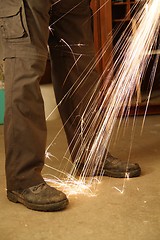 Image showing Worker with angle grinder only feet