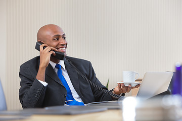 Image showing Businessman talking on telephone while having tea