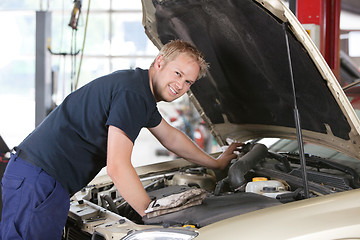 Image showing Smiling mechanic working on car