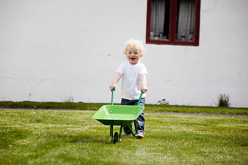 Image showing Young Child Pushing Wheelbarrow