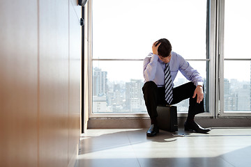 Image showing Upset Business man Sitting on Briefcase