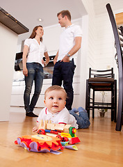 Image showing Baby Playing on Floor with Parents in Background