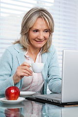 Image showing Woman Working on Laptop While Having Cup of Tea