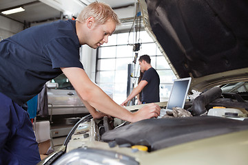 Image showing Mechanic using laptop while working on car