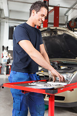 Image showing Smiling young mechanic working on a laptop