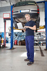 Image showing Portrait of smiling mechanic working on laptop