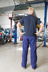 Image showing Mechanic looking at car