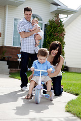 Image showing Cheerful Mother Teaching Son To Ride Tricycle