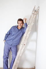 Image showing Smiling man leaning on ladder