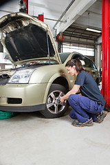 Image showing Female mechanic changing wheel