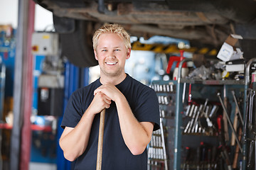 Image showing Smiling mechanic holding broom