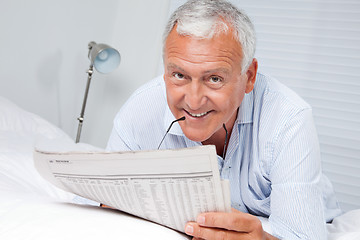 Image showing Man Reading Newspaper on Bed