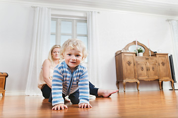 Image showing Baby crawling with mother in the background