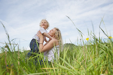 Image showing Mother sitting on grass while playing with boy